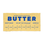 Butter wrapper graphic detail on beach towel with bold blue lettering and measurement markings. Unique novelty design inspired by classic butter packaging.