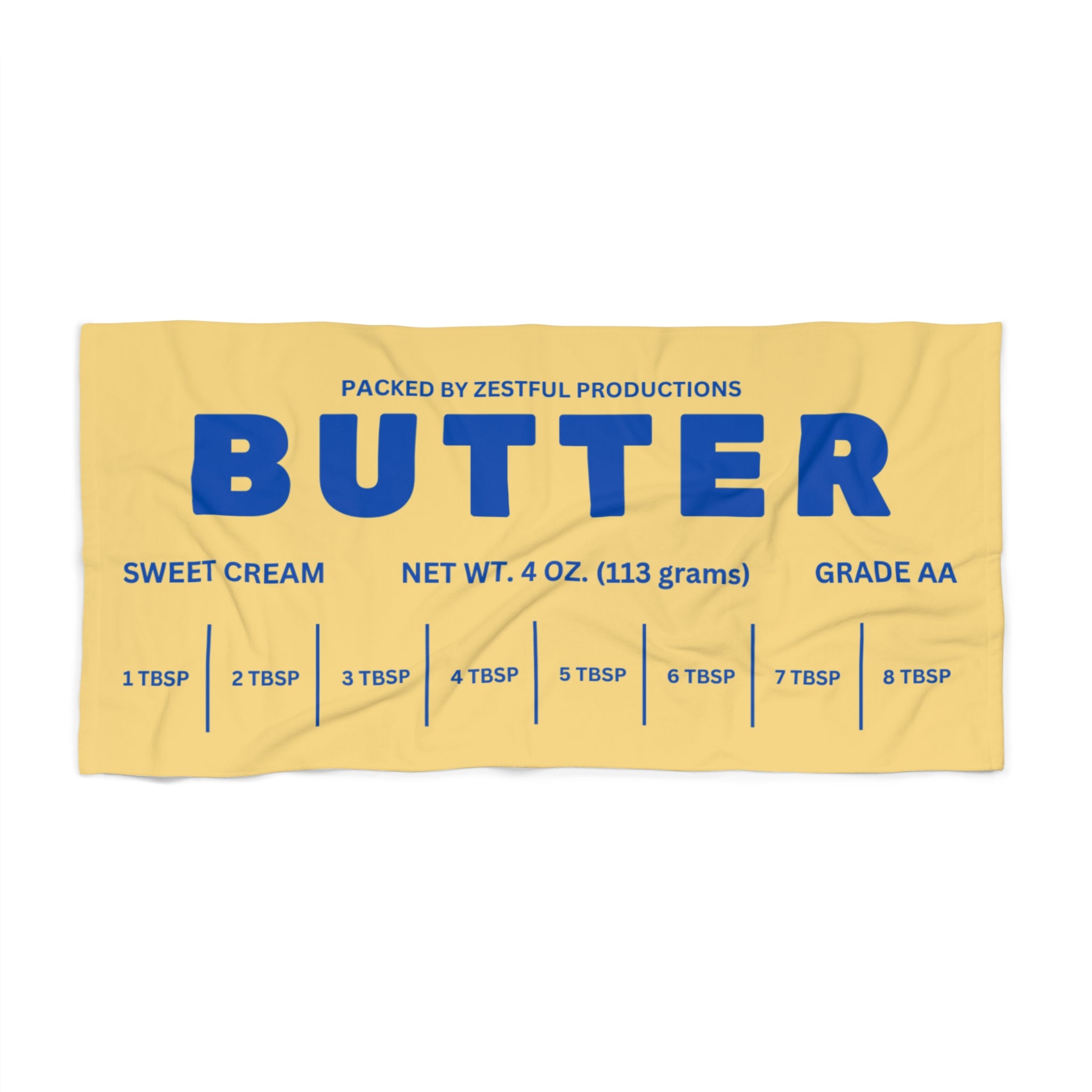 Butter wrapper graphic detail on beach towel with bold blue lettering and measurement markings. Unique novelty design inspired by classic butter packaging.