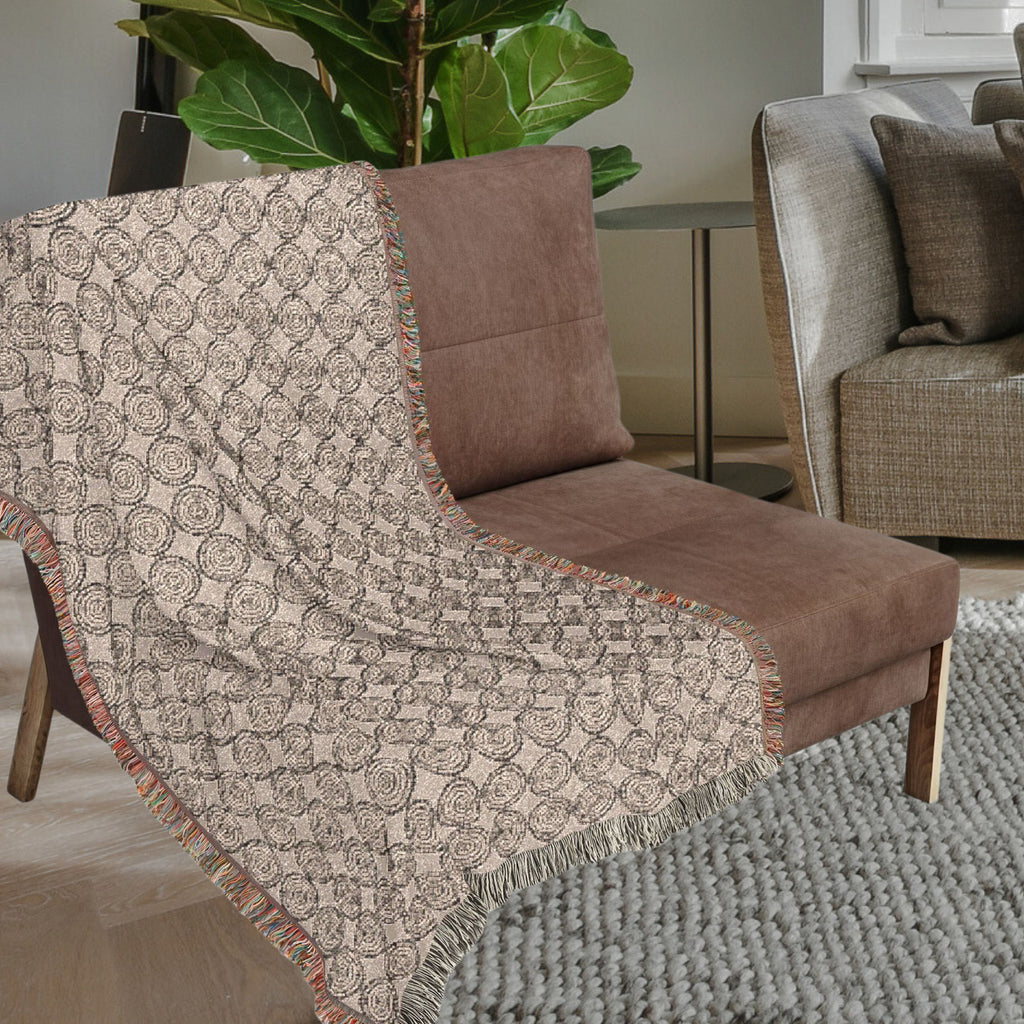 Neutral woven throw blanket with colorful fringe styled on a sofa