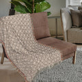 Neutral woven throw blanket with colorful fringe styled on a sofa