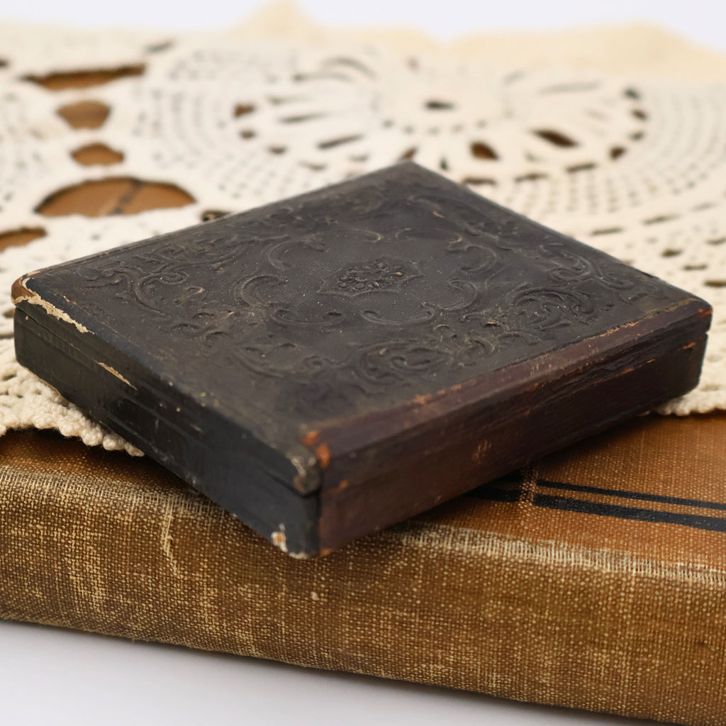 Closed antique Union case featuring its original brass hook closure and richly embossed Victorian decorative design. This protective case preserves a mid-1800s ambrotype glass portrait and reflects the craftsmanship of early American photographic presentation.