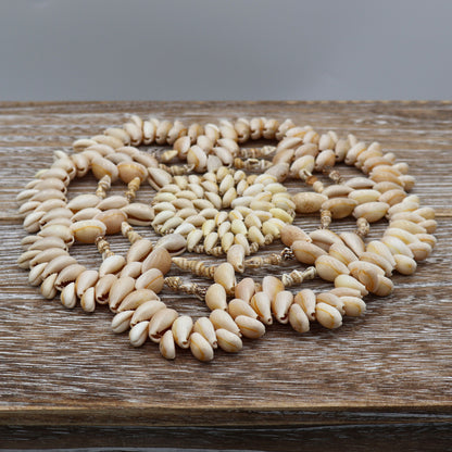 Handmade coastal shell hot pad with layered cowrie shells arranged in circular pattern