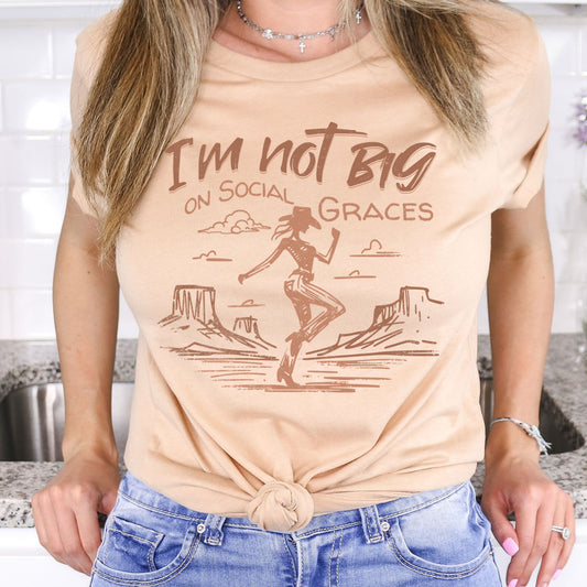 Western graphic tee styled on model with shorts for a casual outfit, featuring cowgirl desert illustration and soft neutral boutique aesthetic