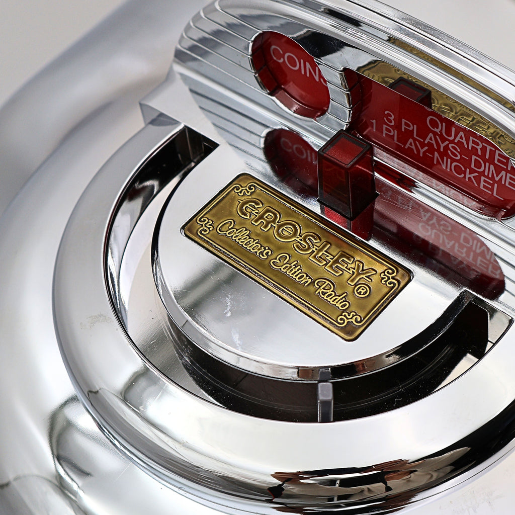 Top detail of Crosley CR-9 jukebox radio coin slot design and collector’s edition badge, retro diner inspired decorative feature with chrome and red accents