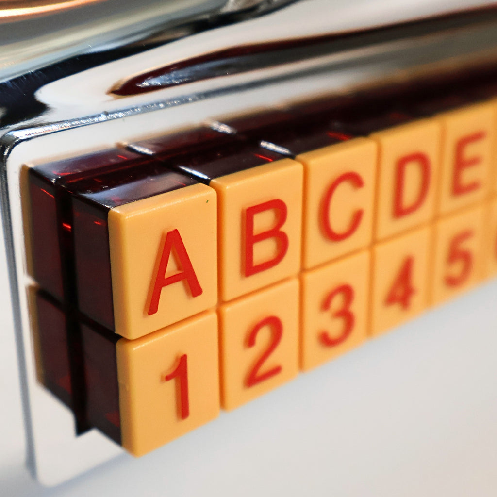 Detail of Crosley CR-9 jukebox radio selection buttons with letter and number controls, retro 1950s diner style interface, nostalgic chrome music player with tactile push buttons