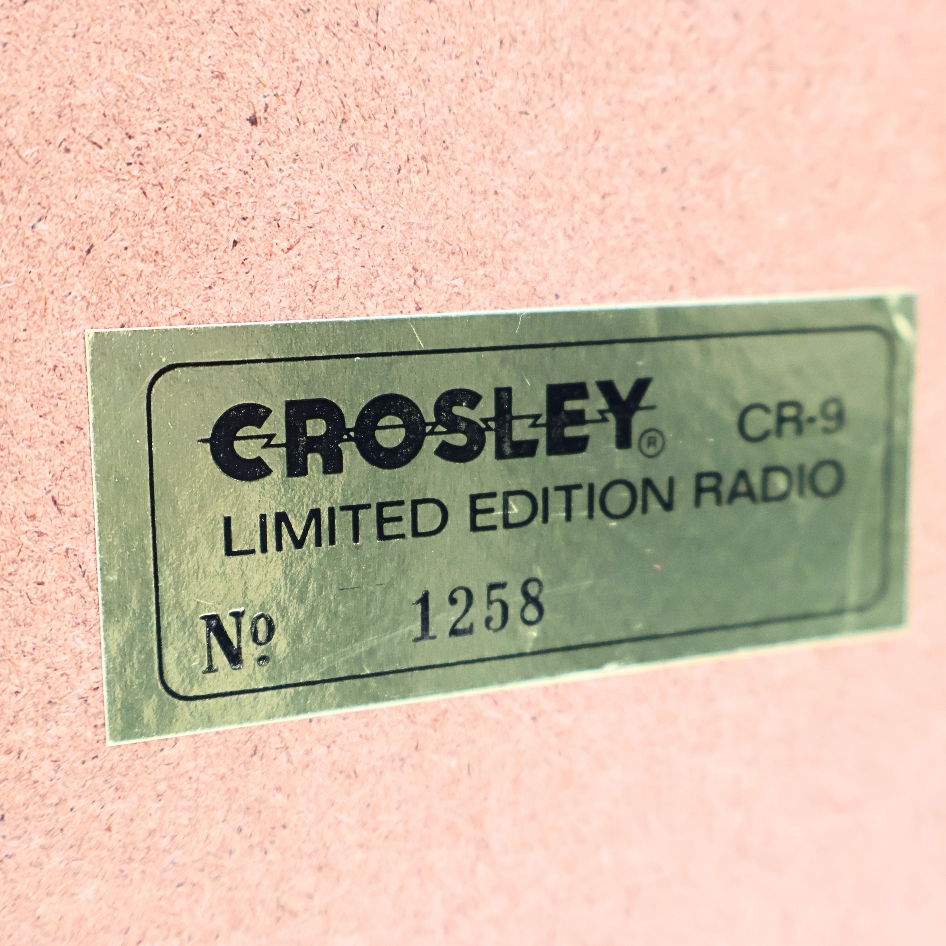 Close up of Crosley CR-9 limited edition jukebox radio badge with serial number plate, collector’s edition marking on vintage style 1950s diner music player, chrome retro decor detail