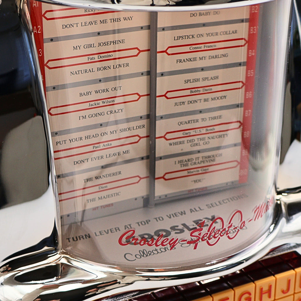 Close up of Crosley CR-9 jukebox radio song selection display showing classic track listings, illuminated rotating selector, vintage diner style music player detail with nostalgic mid century design