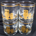 Four Culver owl lowball glasses arranged in a compact stacked display. The front-facing pair of clear tumblers shows textured gold adult and smaller owls perched together, with matching gold rim bands creating a cohesive mid-century barware set.