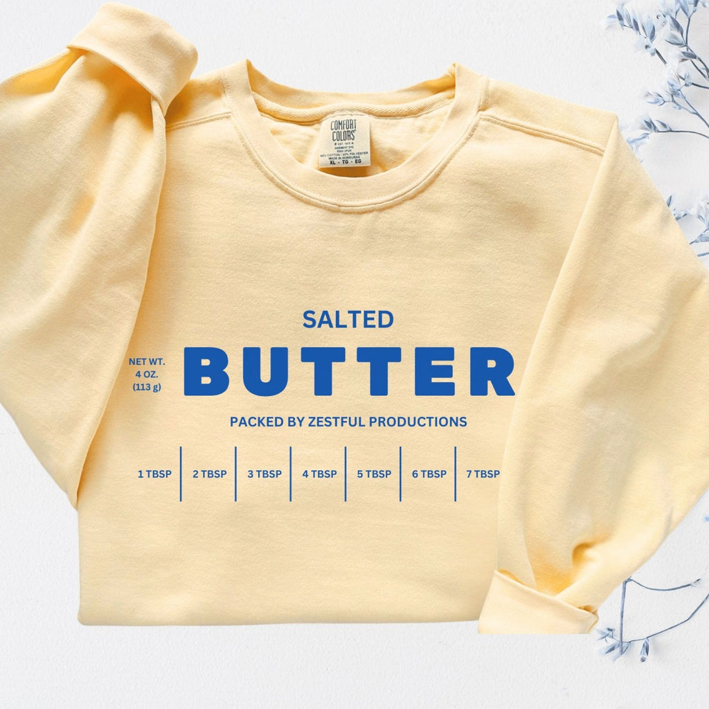 Folded personalized butter sweatshirt showing clean butter label graphic. Customizable cozy crewneck in soft garment dyed fabric.