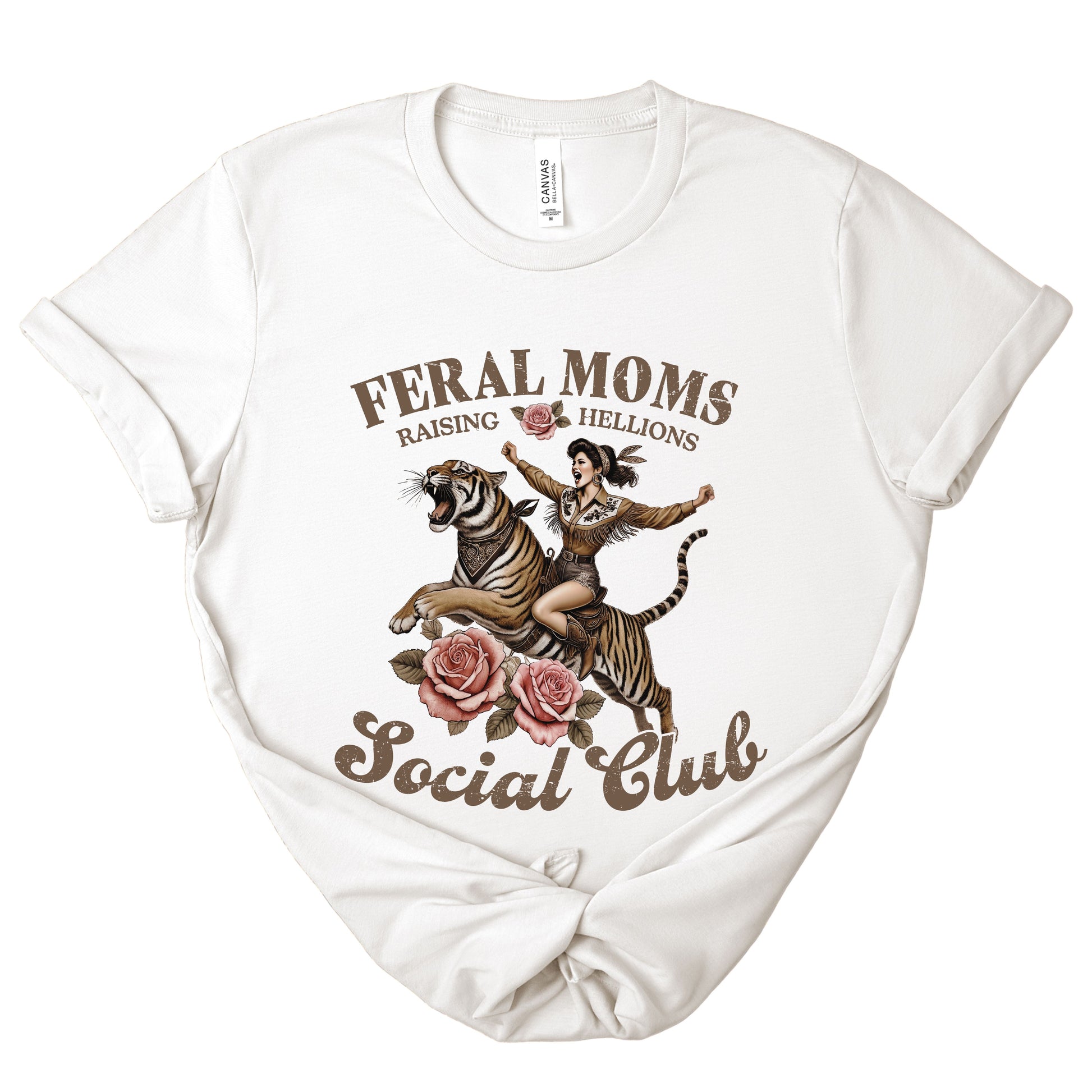 White t-shirt with graphic design of a woman riding a tiger and text 'Feral Moms Raising Hellions Social Club' on a white background.