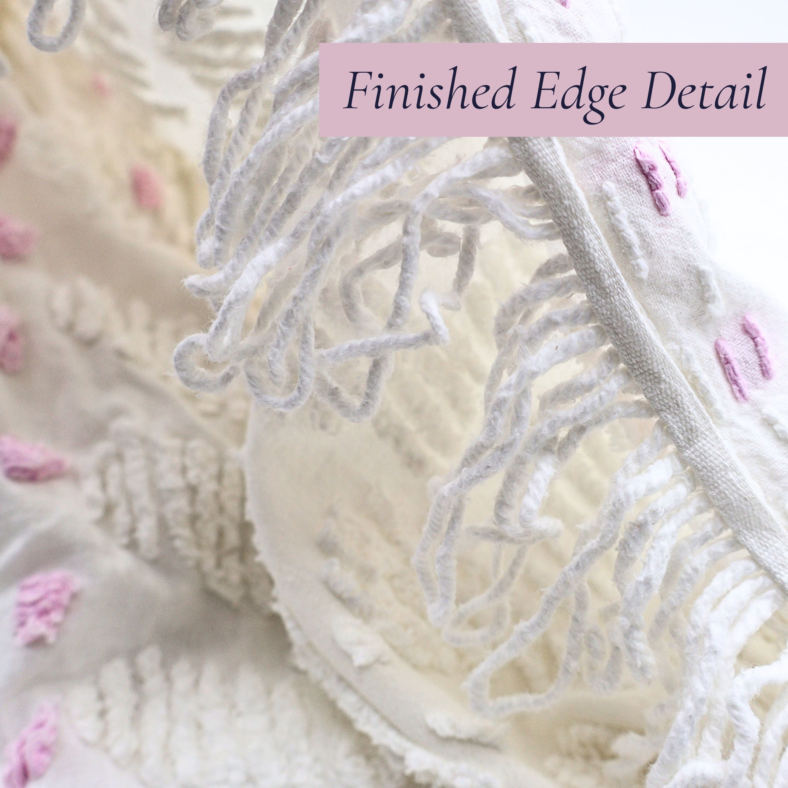 Close-up of the finished edge and woven construction on a vintage white chenille bedspread with lavender floral detailing. The original craftsmanship and decorative border make this heirloom textile perfect for farmhouse decor, cottage bedrooms, and vintage home styling.