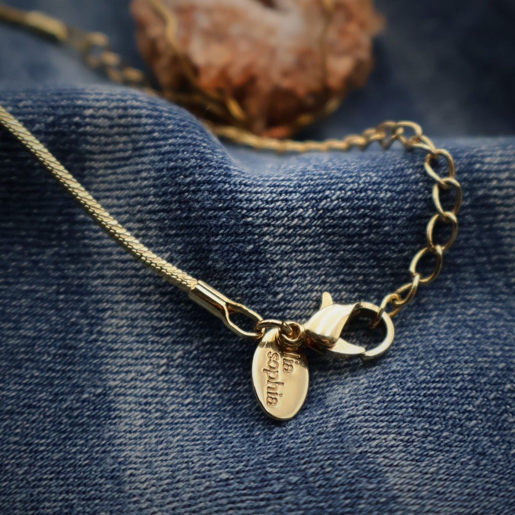 Close-up of gold chain lobster clasp with extension links and Lia Sophia tag, adjustable necklace length detail for handmade druzy quartz geode pendant, secure closure design for everyday wear boho western jewelry