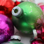Closeup of vintage green pink and silver mercury glass Christmas ornaments with reflective retro holiday styling