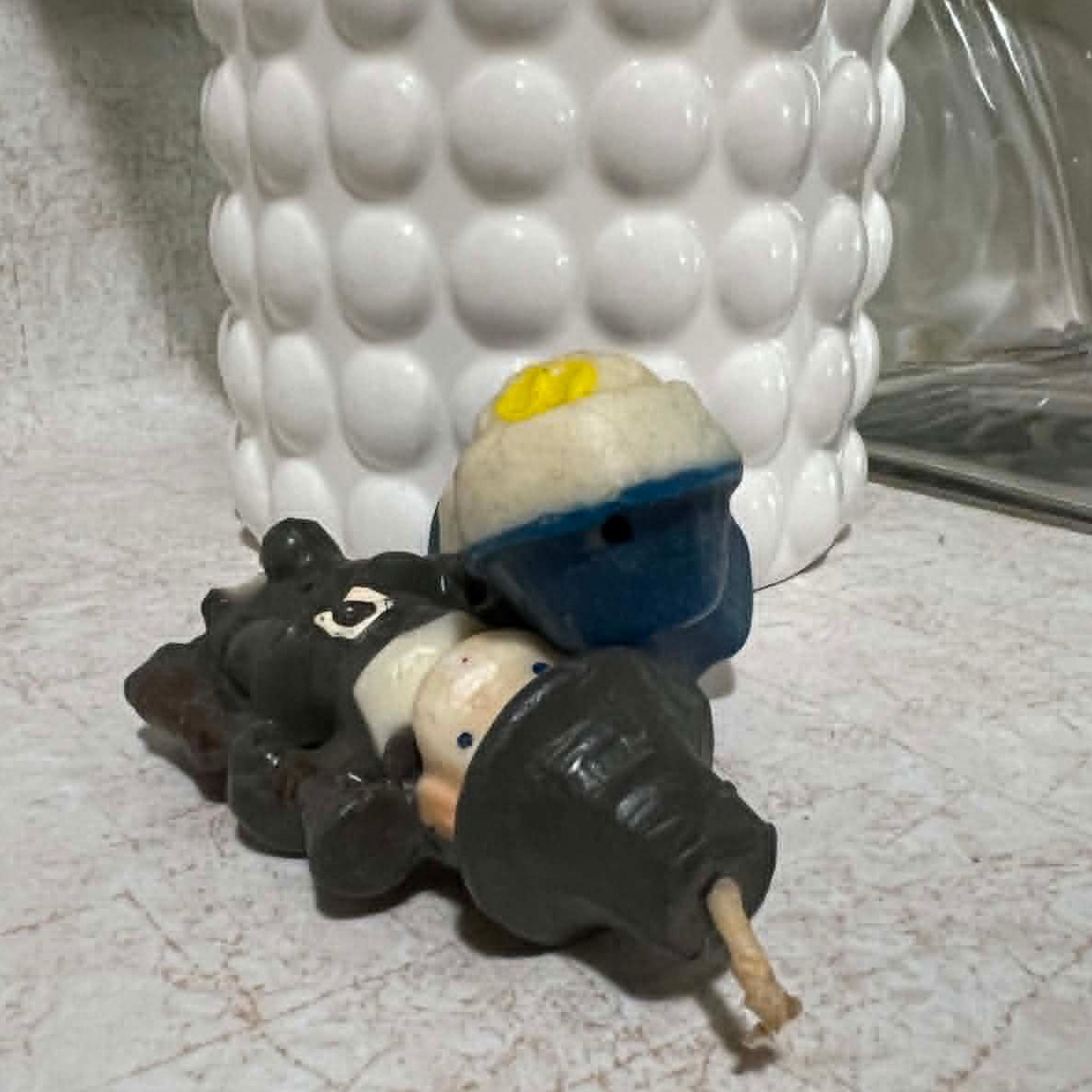Vintage Gurley Thanksgiving pilgrim candles positioned to show their upper surfaces, molded wax construction and condition. The male pilgrim's long intact wick is clearly visible along with his dark hat, while the blue female figure shows age-related wear and discoloration.