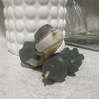 Close condition view of vintage Gurley pilgrim candles showing the intact unused wicks and upper portions of both molded wax figures. Visible age-related discoloration appears near the female pilgrim's head while the dark wax clothing shows expected vintage surface wear.