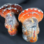 Overhead front close-up showing the faces and fan-shaped tails of two vintage Gurley turkey candles. The photograph reveals black, brown and orange painted wax, white areas of color loss along the feather edges, red wattles, molded feather texture and surface scuffing.