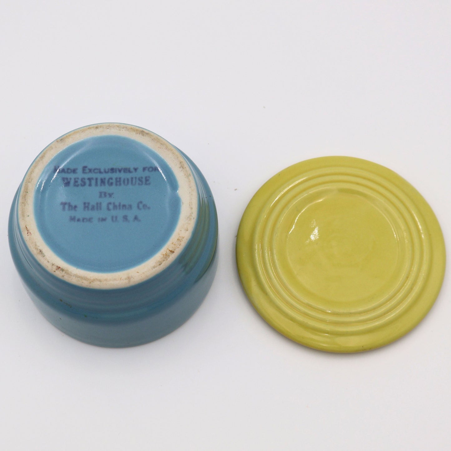 Flat lay of Hall China Westinghouse refrigerator dish base and lid showing underside stamp and vintage glaze finish.