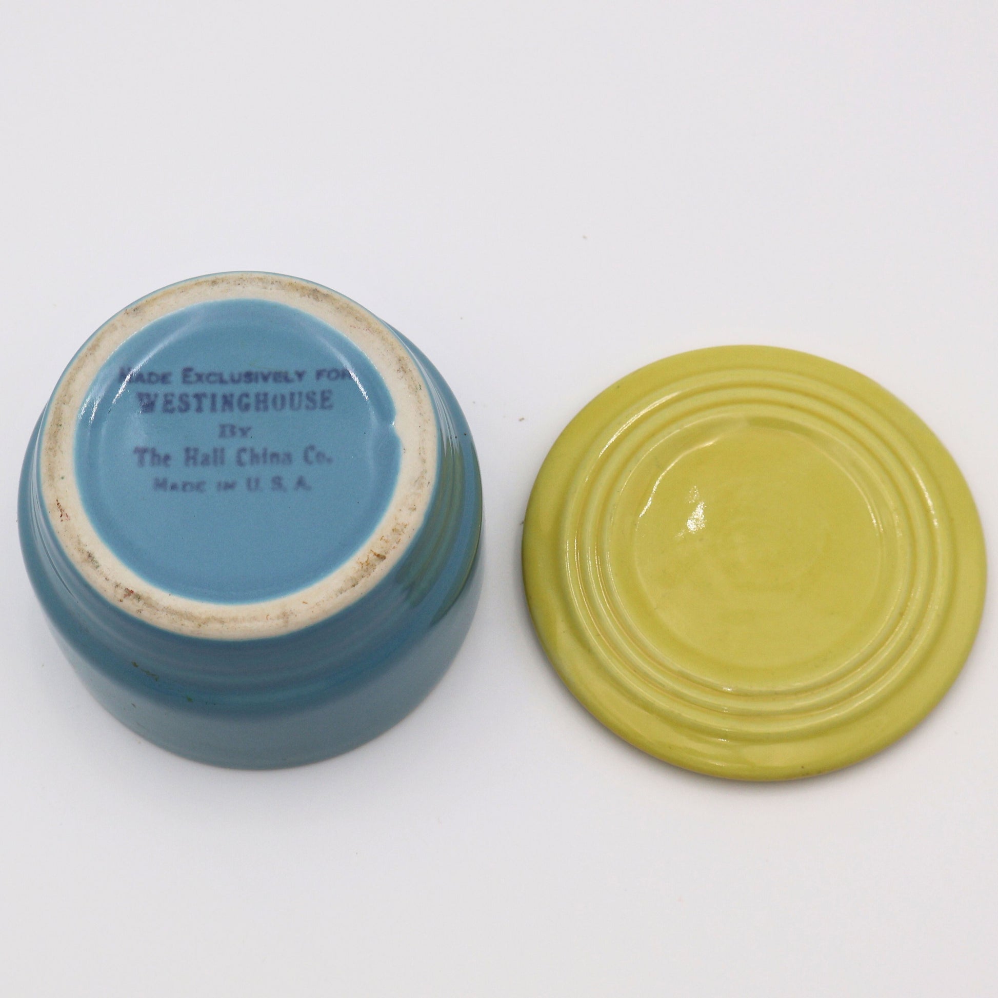 Flat lay of Hall China Westinghouse refrigerator dish base and lid showing underside stamp and vintage glaze finish.