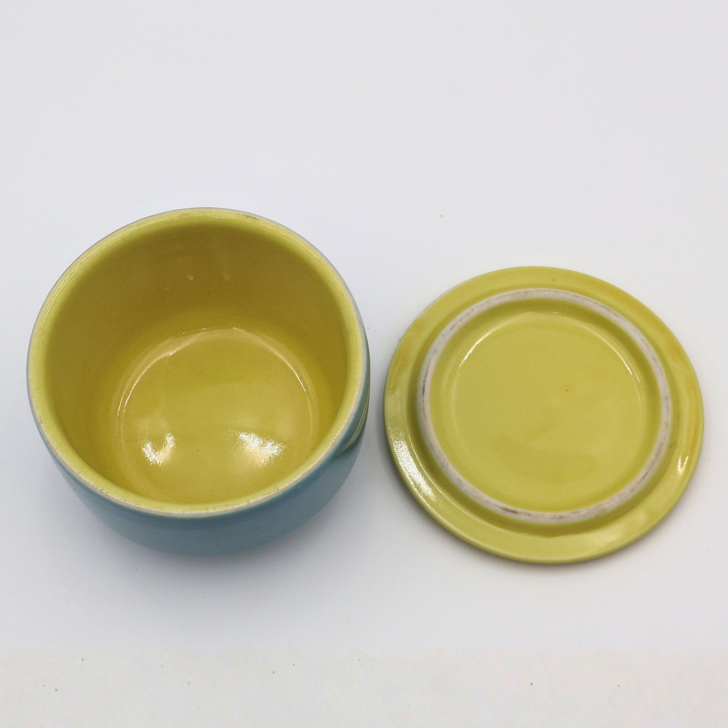 Top view of Hall China refrigerator crock showing butter yellow interior and matching yellow lid with concentric ring detail.