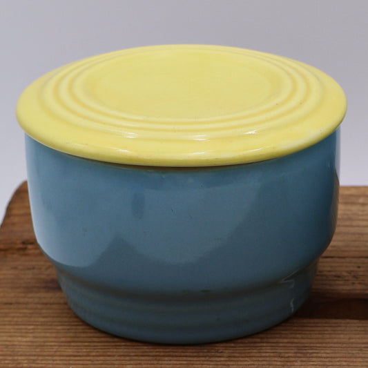 Vintage Hall China Westinghouse refrigerator dish with butter yellow lid and blue base, mid century American kitchen crock front view.