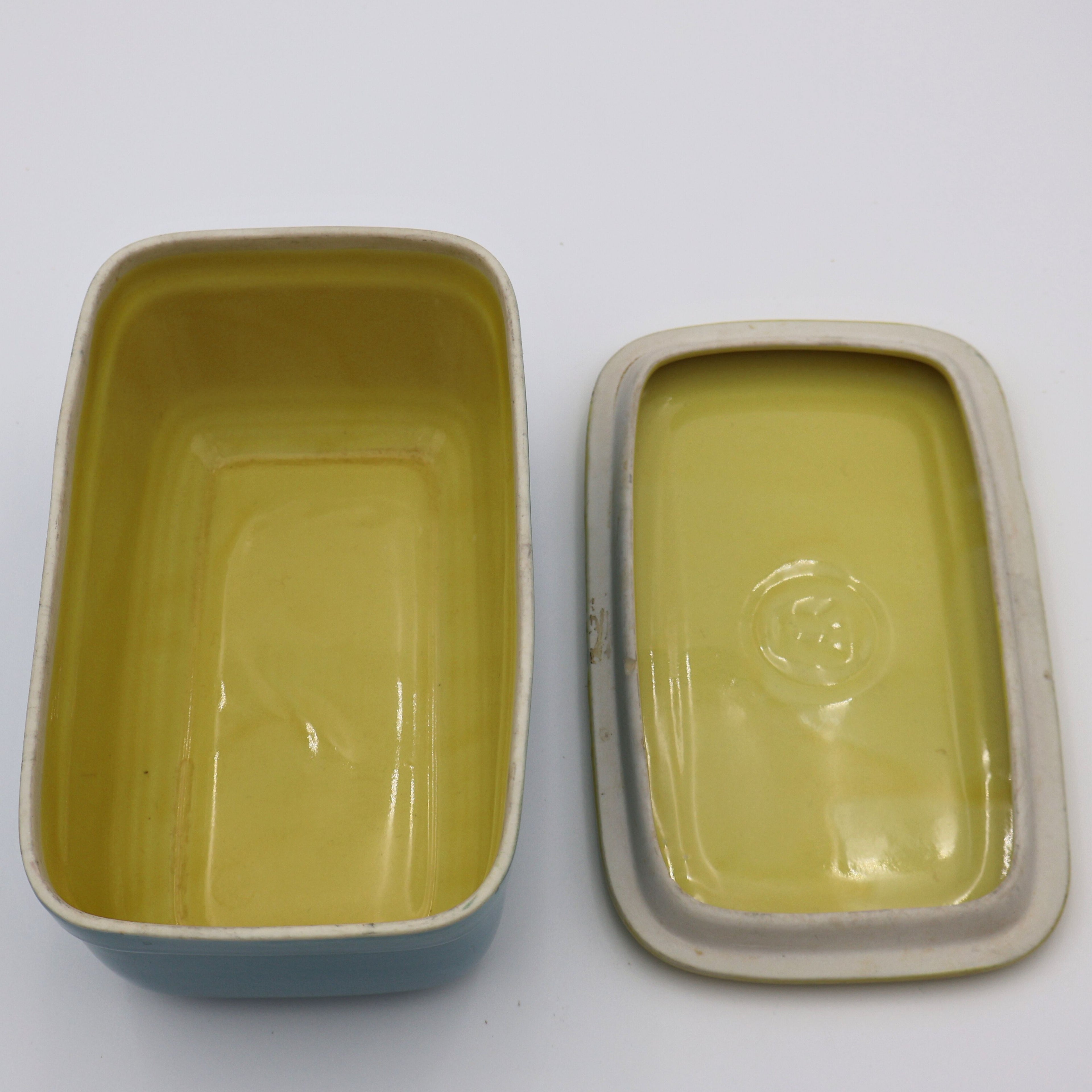 Inside view of vintage Hall China Westinghouse refrigerator dish with embossed W on yellow lid.