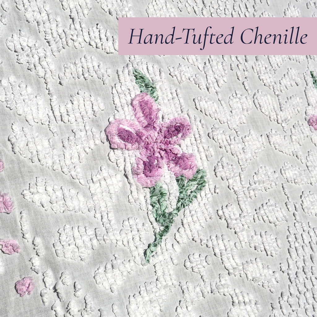 Detailed view of an original hand-tufted lavender flower on a vintage white chenille bedspread. The soft raised chenille texture showcases classic vintage craftsmanship and makes this heirloom textile ideal for cottagecore decor, farmhouse homes, and romantic bedroom styling.