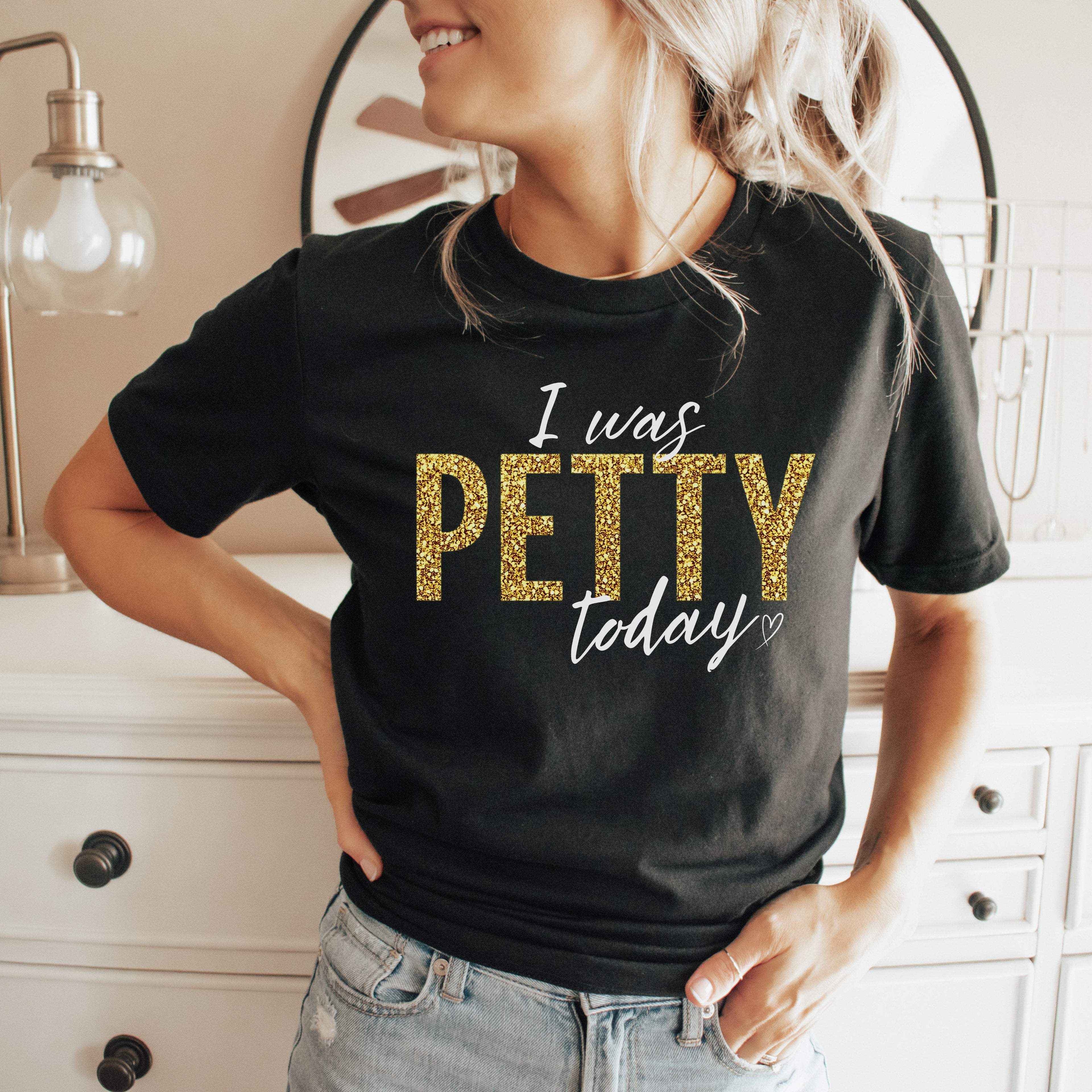 Woman wearing black “I Was Petty Today” gold faux glitter graphic tee, casual outfit with jeans, funny sarcastic statement shirt for women, everyday wearable boutique fashion