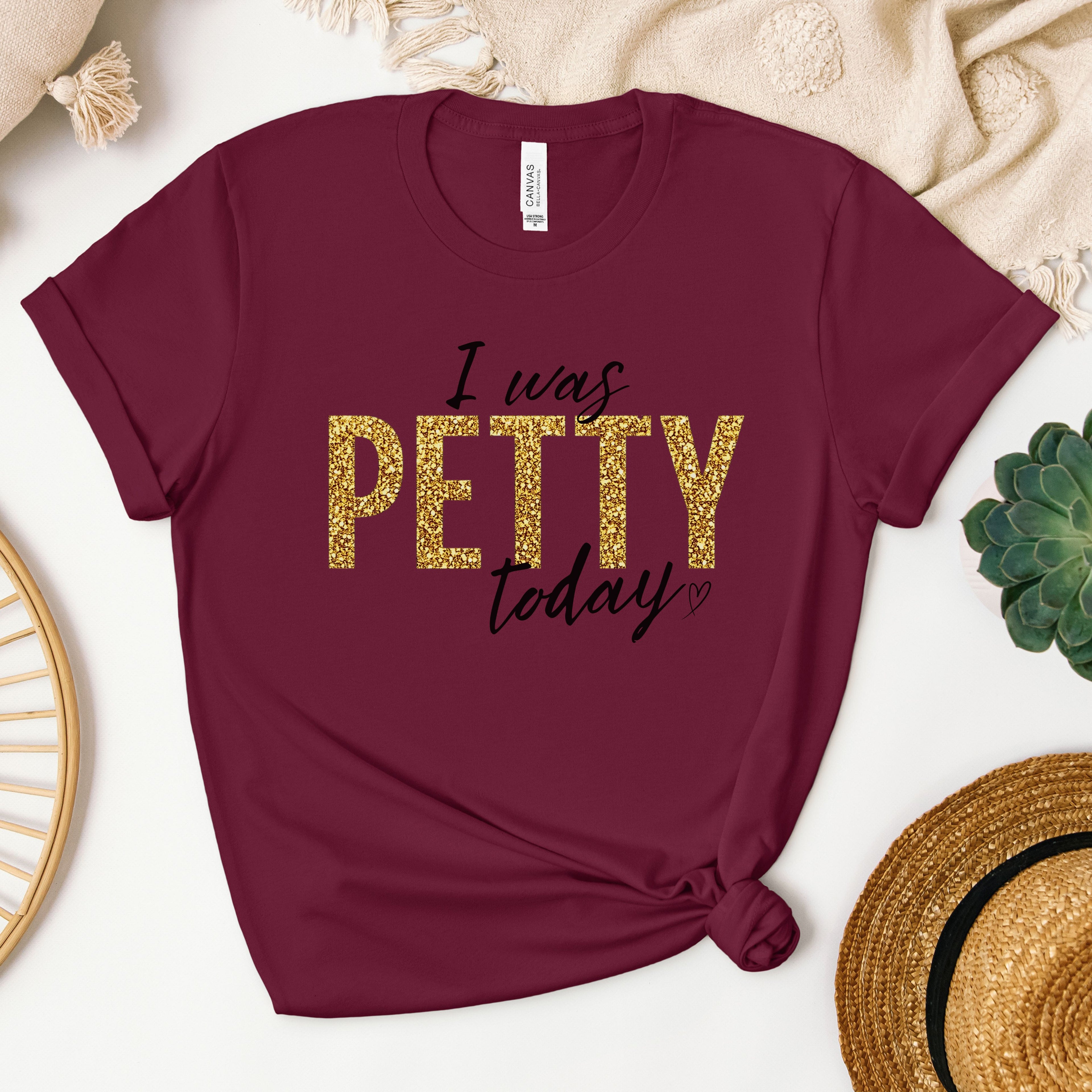 Burgundy t-shirt with gold faux glitter “I Was Petty Today” design, rich bold color flat lay, funny sarcastic women’s shirt, boutique statement tee