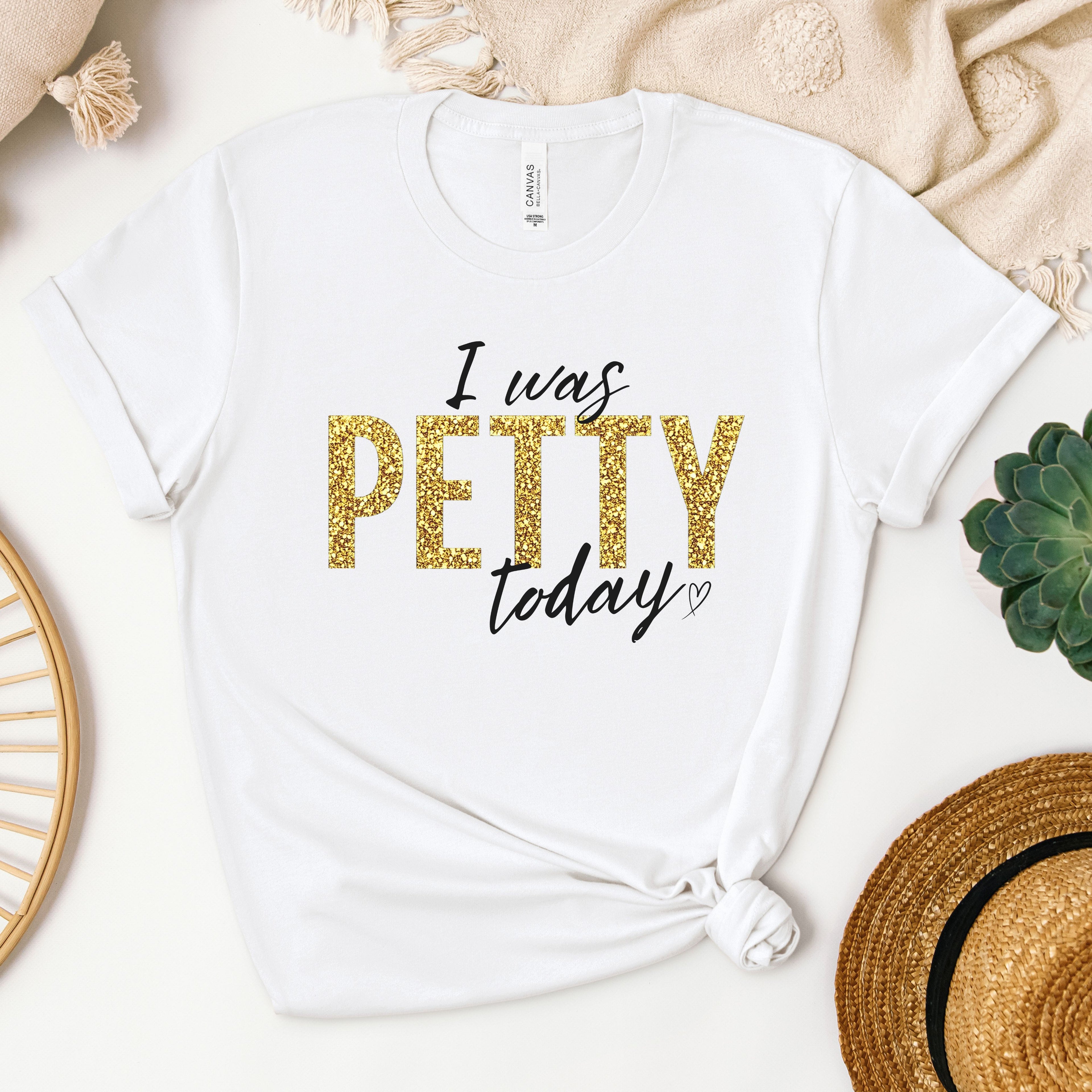 White Bella Canvas t-shirt with “I Was Petty Today” gold faux glitter graphic design, flat lay mockup with neutral styling, funny sarcastic statement tee for women, soft casual boutique apparel