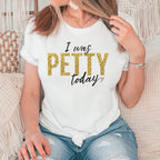 Woman wearing white “I Was Petty Today” gold faux glitter graphic t-shirt, relaxed casual outfit, cute sarcastic statement tee for women, soft comfortable everyday style