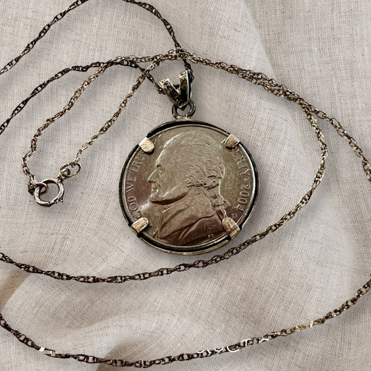 sterling silver Jefferson nickel necklace displayed on neutral fabric flat lay, authentic 2004 US coin pendant jewelry with 18 inch chain, vintage coin necklace styled for minimal aesthetic, collectible Americana jewelry piece for layering or everyday wear
