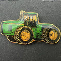 Detailed front view of John Deere tractor enamel pin highlighting green and yellow tractor design with gold tone outline, classic farm equipment style, vintage lapel pin for farmers, tractor enthusiasts, and western inspired outfits