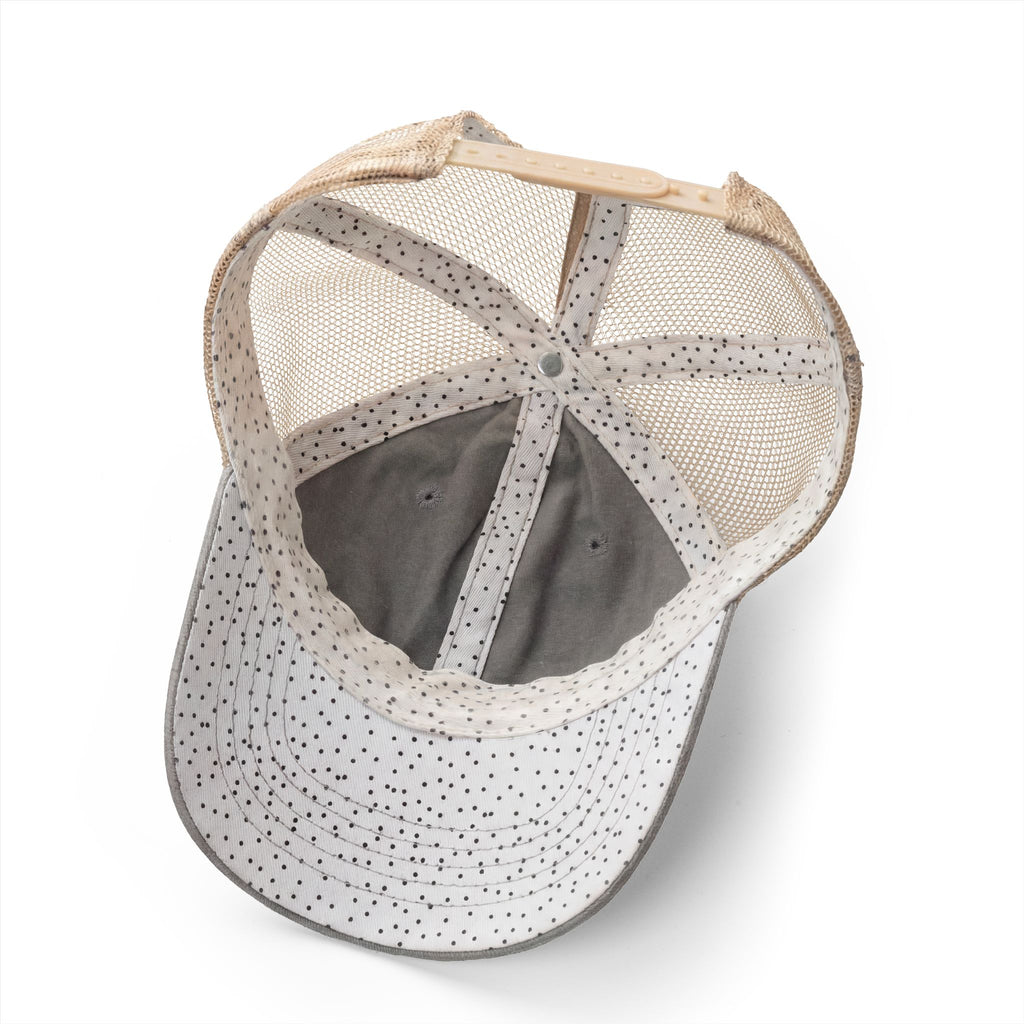 Interior detail of women’s trucker hat featuring black polka dot underbrim print and concealed ponytail opening