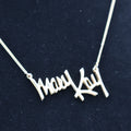 Close-up of vintage Mary Kay Lady gold script pendant necklace worn on display bust, collectible jewelry piece.