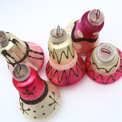 Top view of vintage West Germany bell ornaments featuring atomic black glitter detailing and pink mercury glass finishes