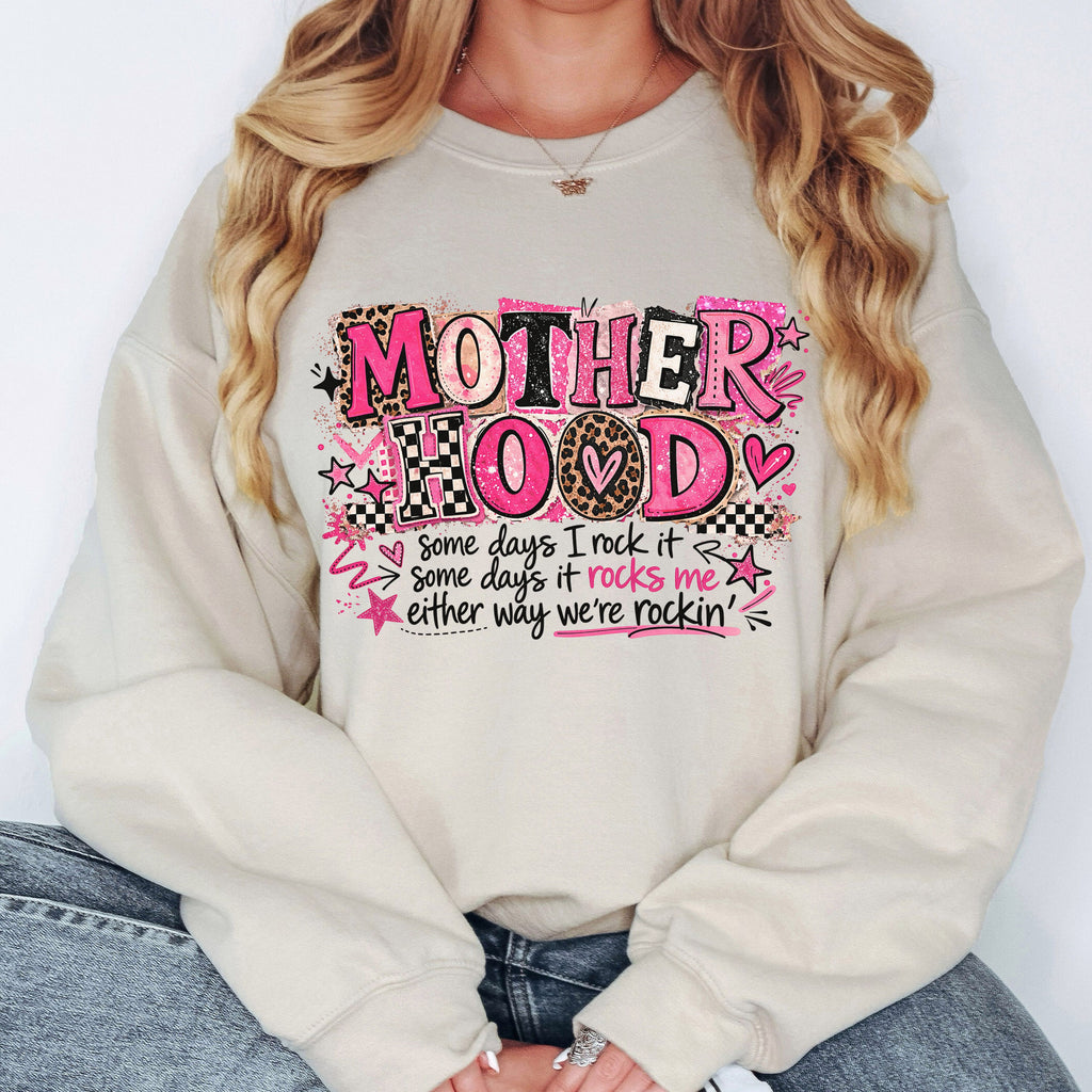 Woman wearing cream Mother Hood graphic sweatshirt featuring pink leopard typography and cozy boutique mom style aesthetic.