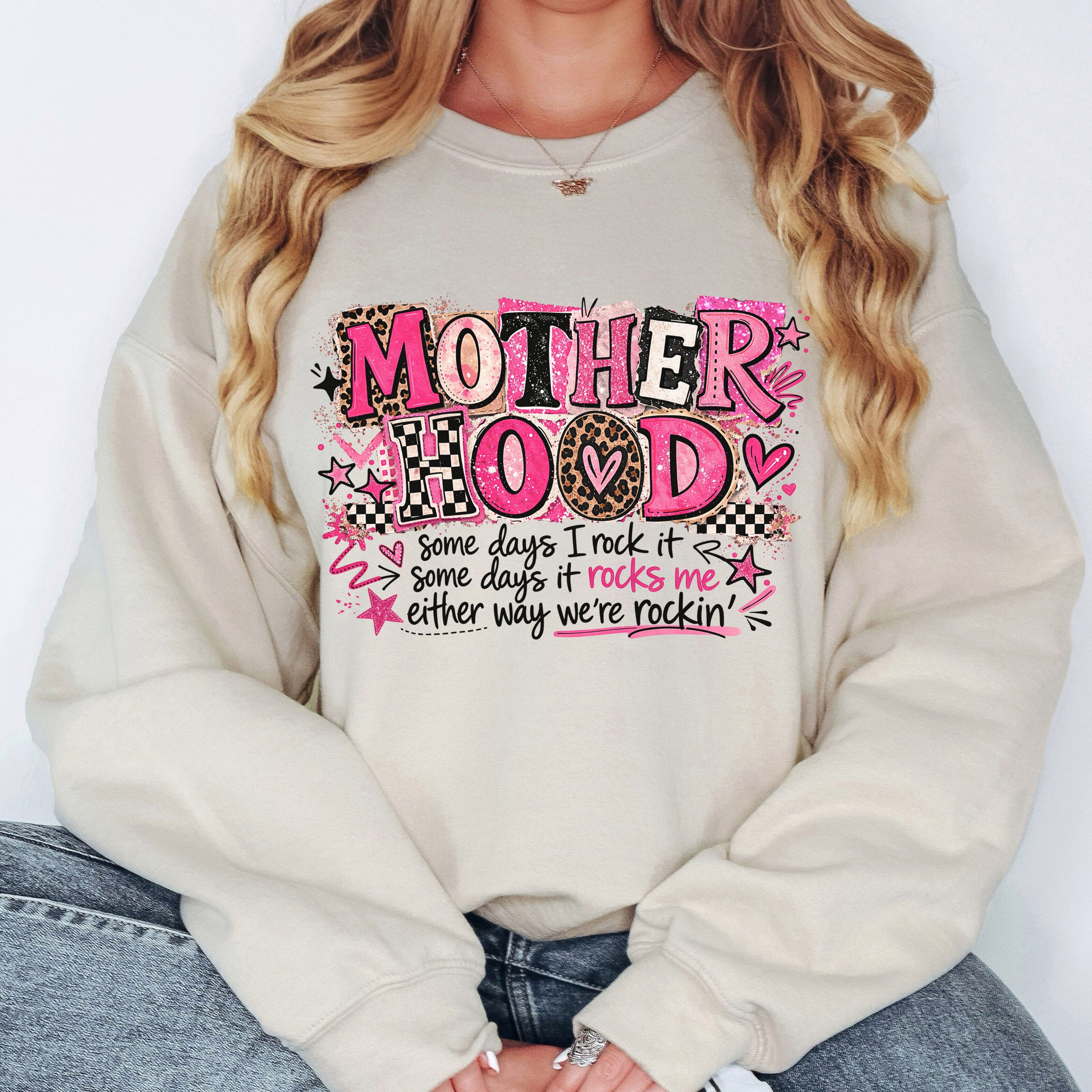 Woman wearing cream Mother Hood graphic sweatshirt featuring pink leopard typography and cozy boutique mom style aesthetic.