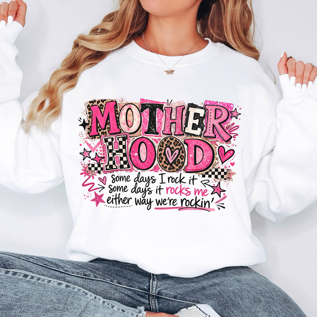 Woman wearing oversized white Mother Hood graphic sweatshirt with trendy pink leopard lettering and motherhood quote.