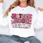 Woman wearing oversized white Mother Hood graphic sweatshirt with trendy pink leopard lettering and motherhood quote.