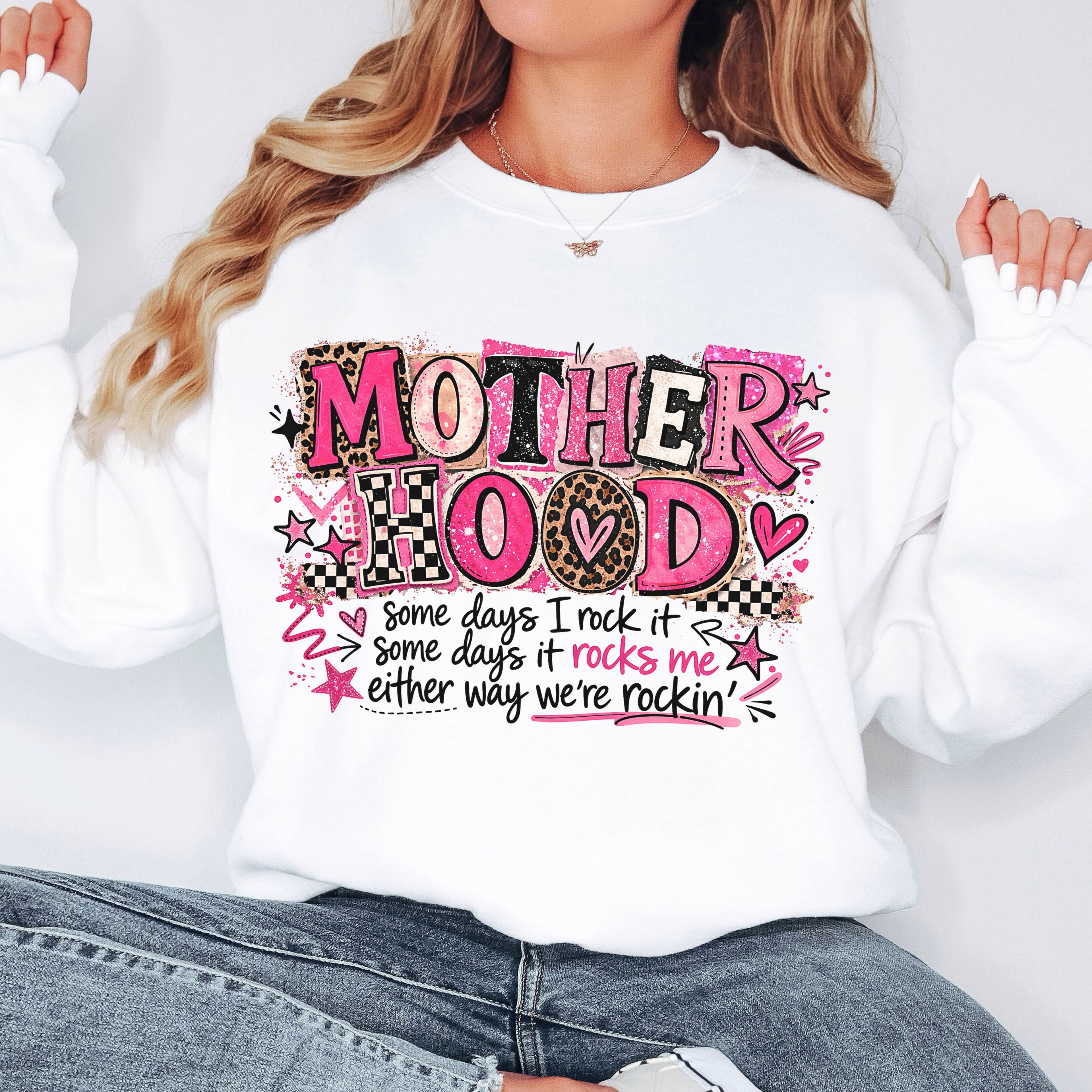 Woman wearing oversized white Mother Hood graphic sweatshirt with trendy pink leopard lettering and motherhood quote.
