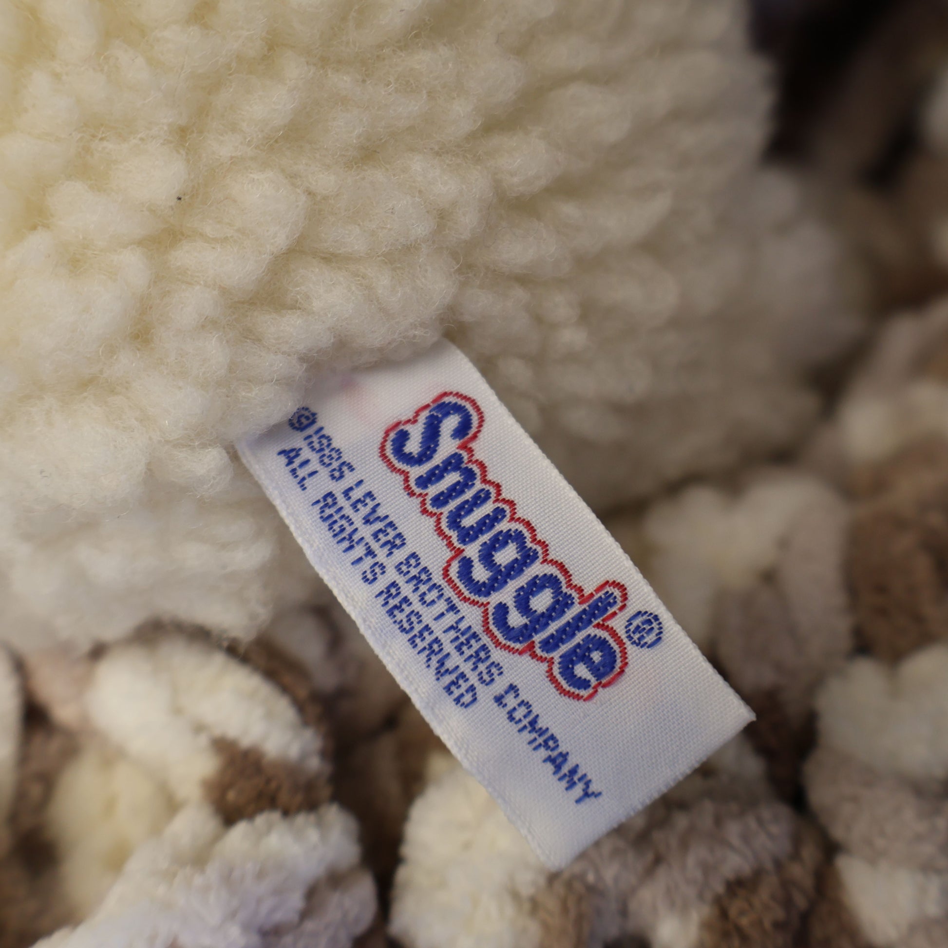 Detailed close-up of the original Snuggle tag showing Lever Brothers branding on an authentic 1986 plush mascot. Original tags enhance collector appeal for vintage advertising enthusiasts and lovers of nostalgic household memorabilia.