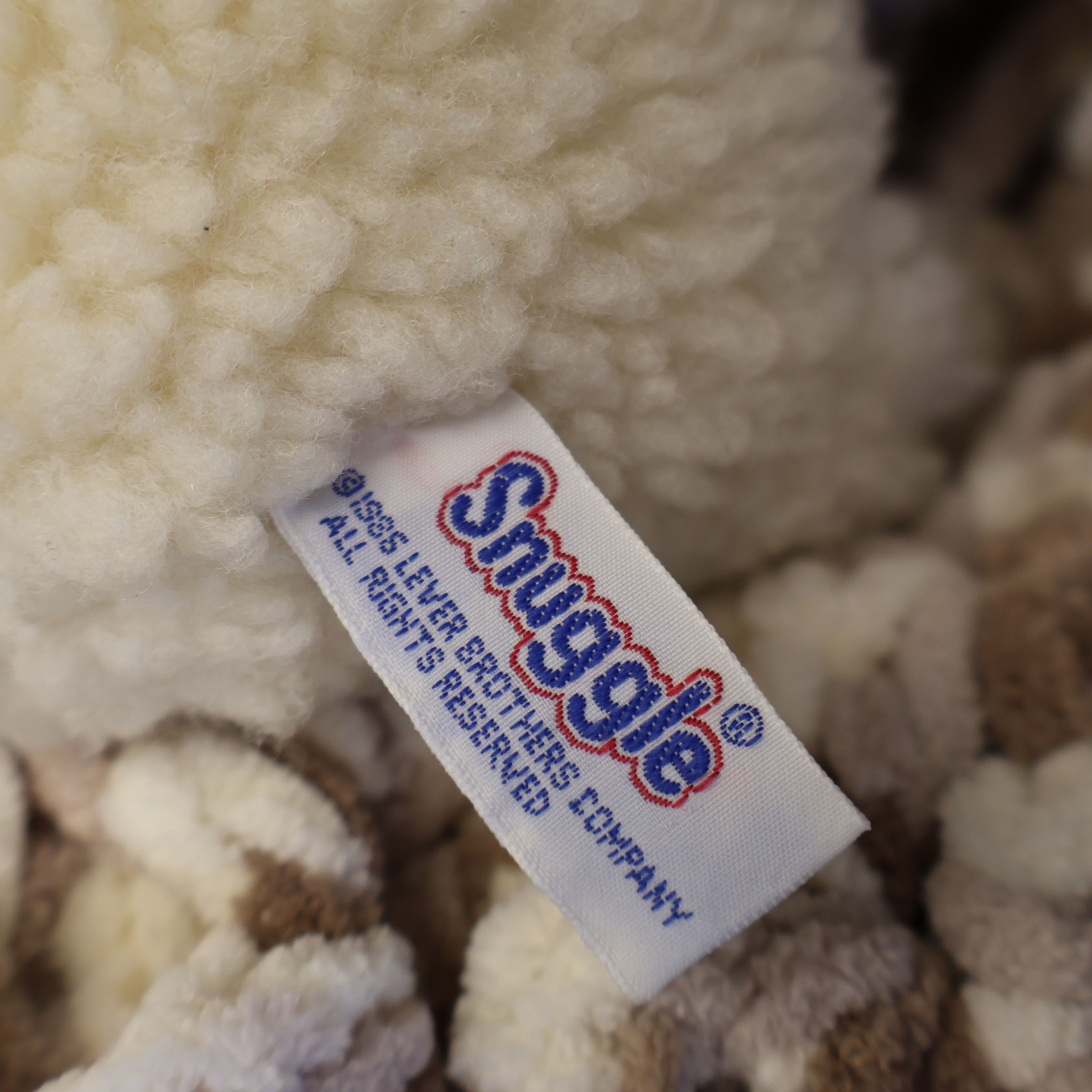 Detailed close-up of the original Snuggle tag showing Lever Brothers branding on an authentic 1986 plush mascot. Original tags enhance collector appeal for vintage advertising enthusiasts and lovers of nostalgic household memorabilia.