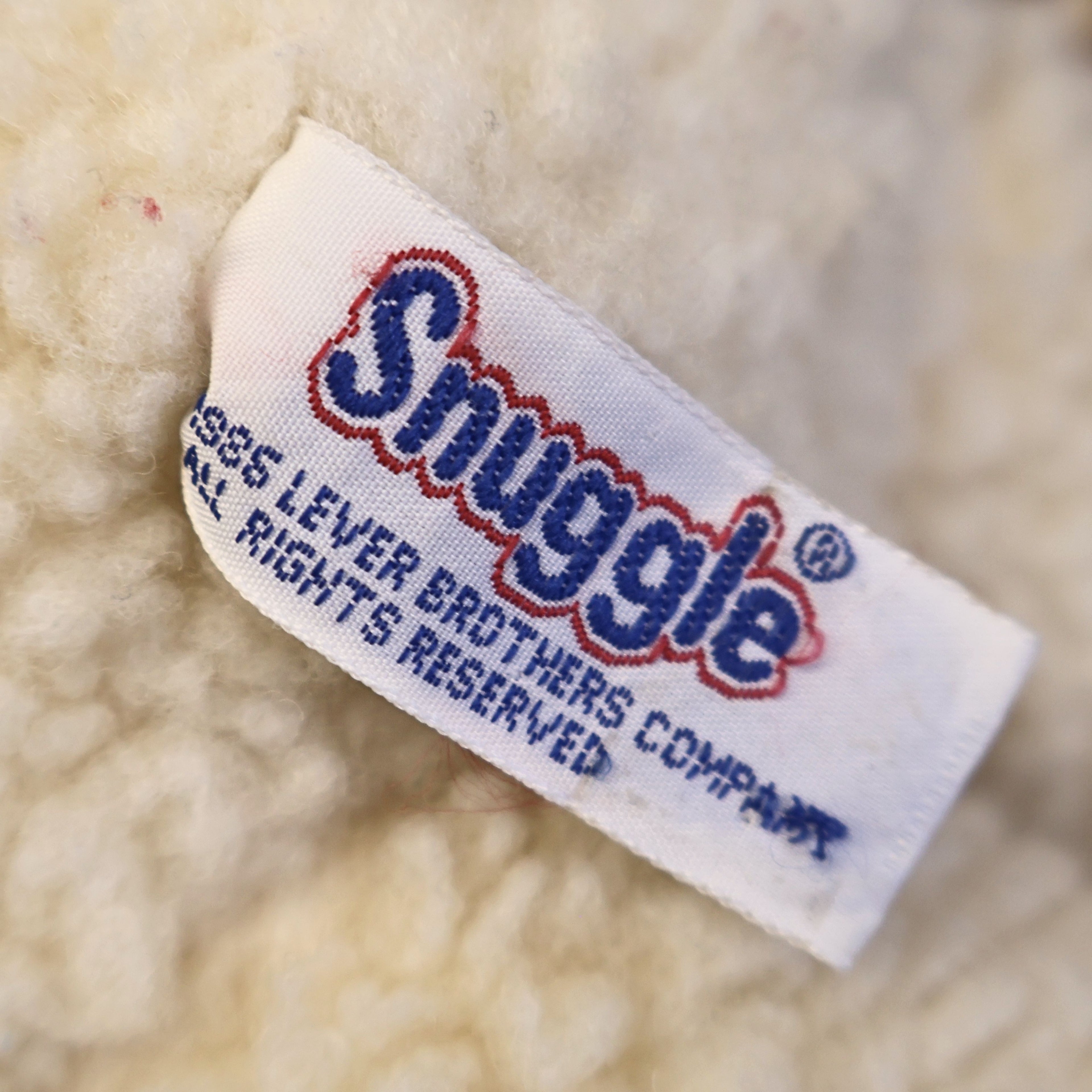 Close-up of the original Snuggle by Lever Brothers fabric tag attached to this authentic 1986 plush mascot. The clear copyright label adds collector appeal and confirms its vintage advertising heritage, making it desirable for retro memorabilia and nostalgic toy collections.