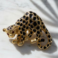 Vintage Park Lane cheetah brooch pin in gold-tone metal with black enamel spots and red rhinestone eyes