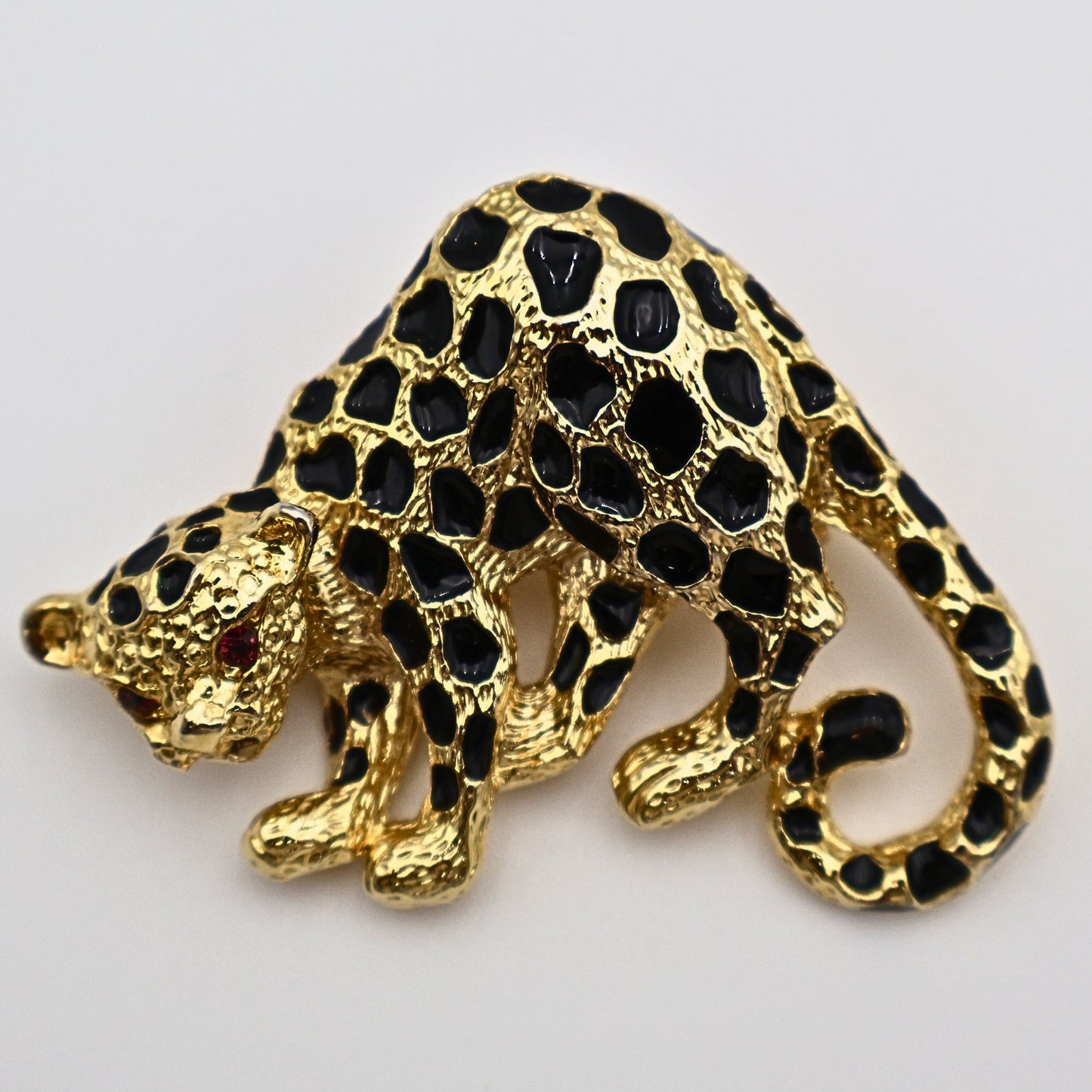 Vintage Park Lane cheetah brooch pin in gold-tone metal with black enamel spots and red rhinestone eyes