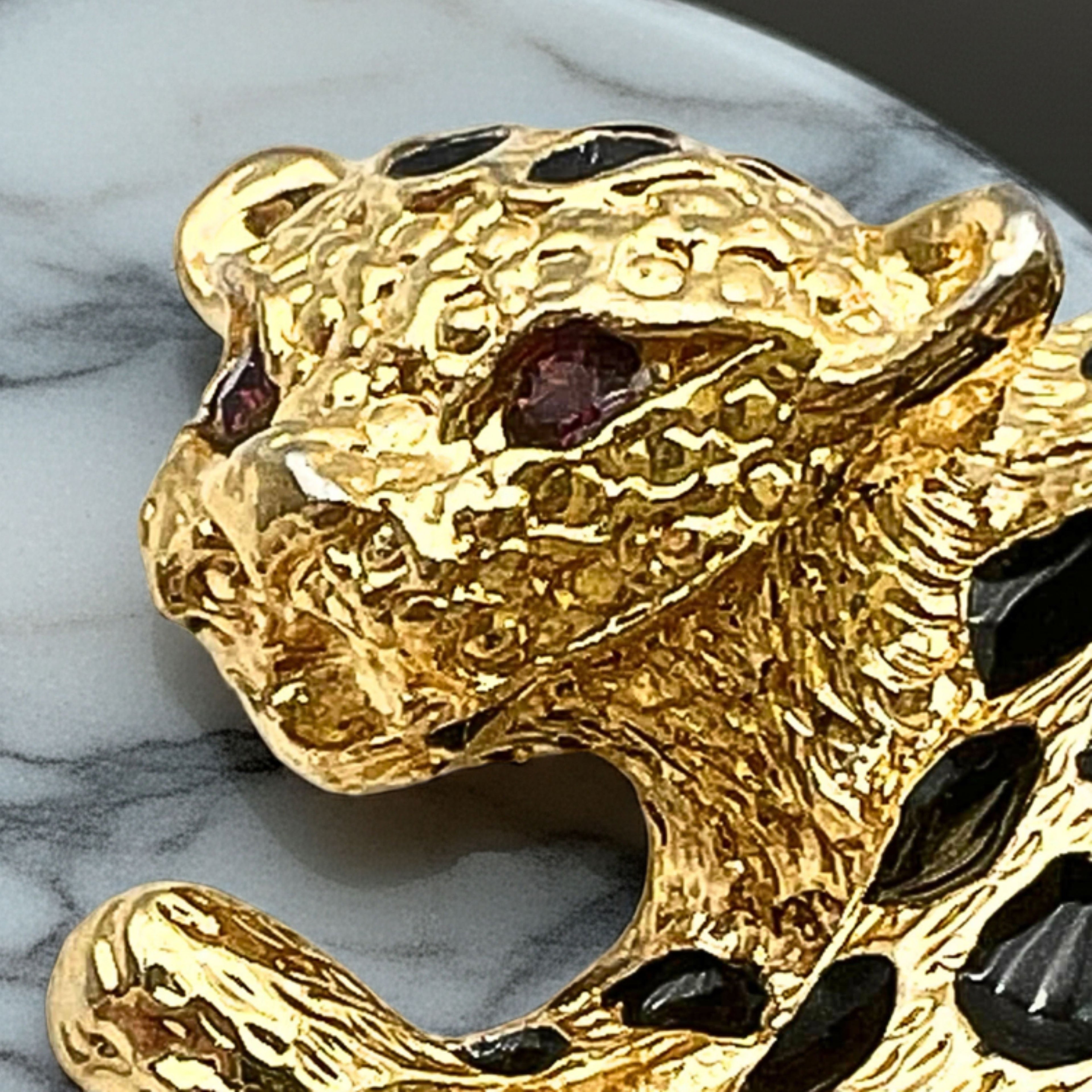 Close-up of rhinestone eyes and black enamel spots on cheetah brooch