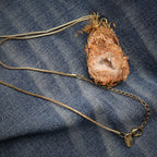 Peach druzy quartz geode necklace displayed flat on denim showing full gold chain, adjustable length design with lobster clasp closure, handmade crystal pendant necklace with boho western styling and natural stone jewelry details