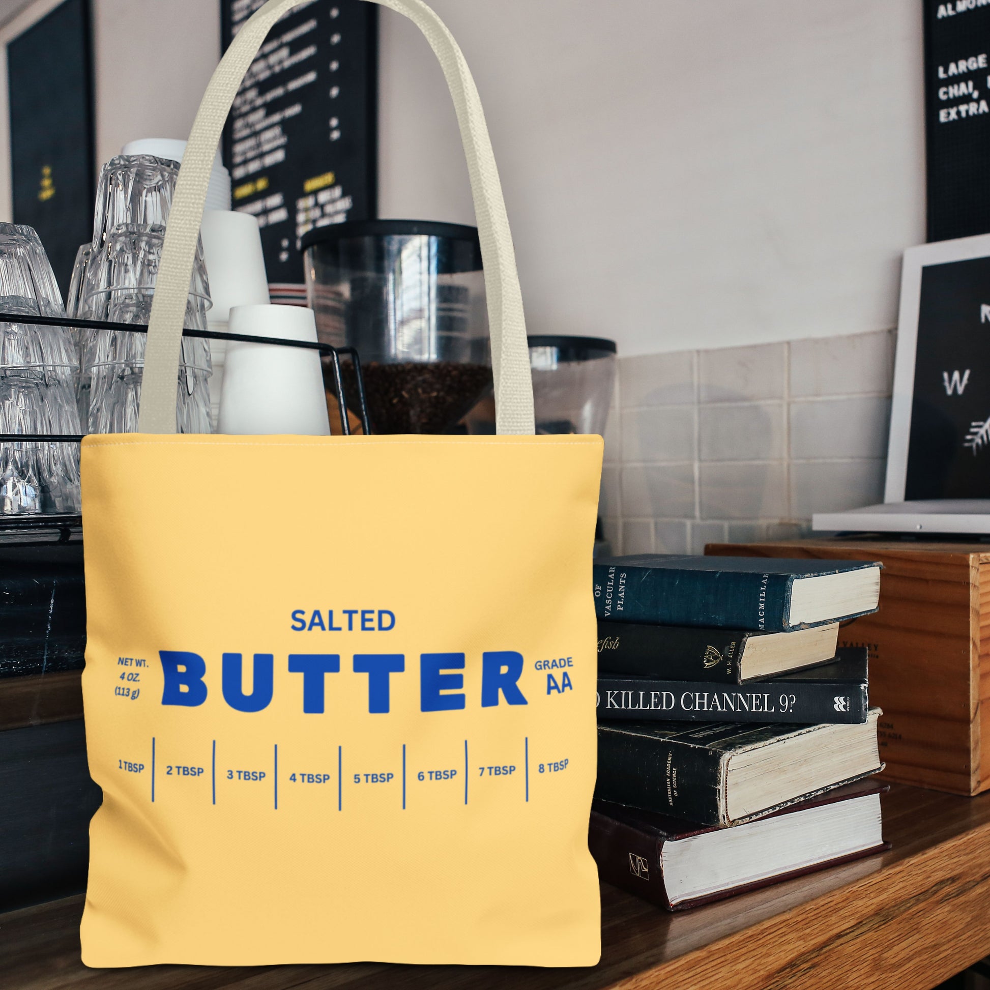 Personalized butter tote bag in yellow with bold blue butter label design, styled next to books. Reusable tote bag perfect for everyday use, shopping, and custom gift ideas.