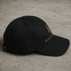 Side profile of black Poopenfarten Motorwerke embroidered dad cap with curved visor and gold logo detail in a clean automotive streetwear aesthetic.