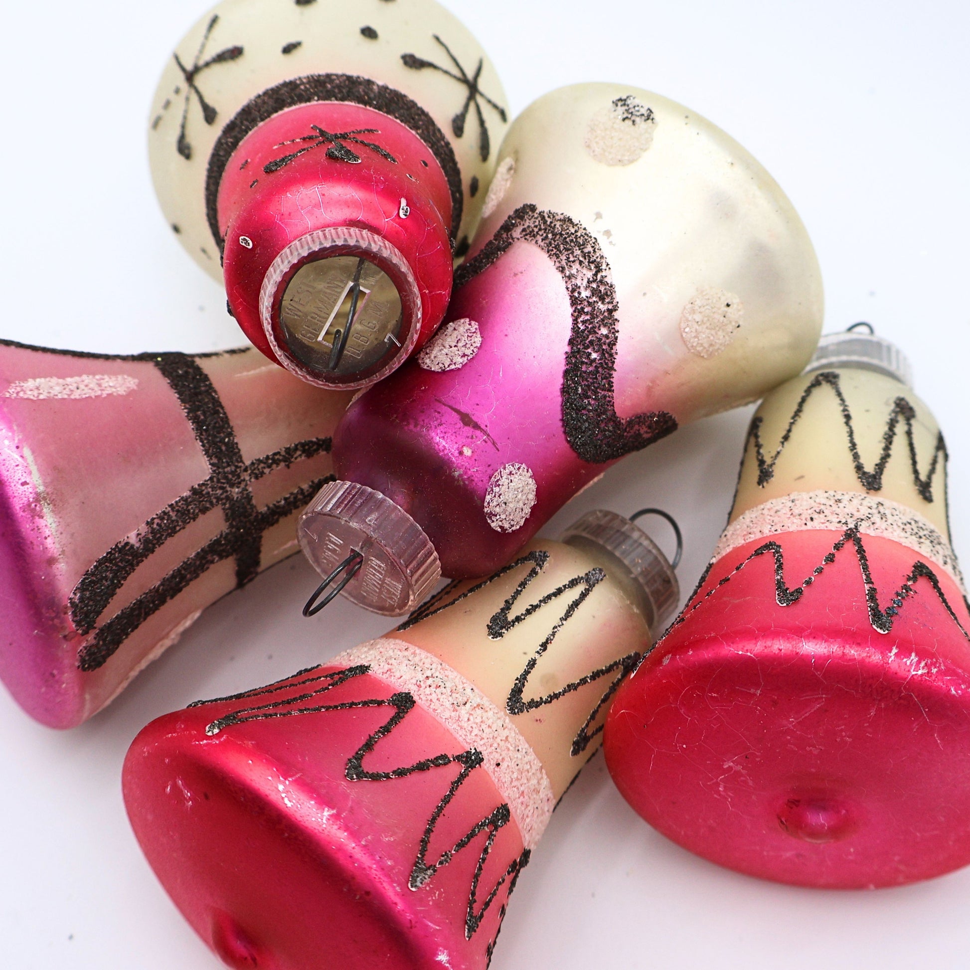 Flat lay of vintage atomic bell ornaments with pink black and cream mercury glass finishes and retro holiday styling
